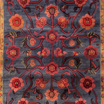 A beautifully intricate Red Bloom Harmony Rug, hand-tufted and perfect for dining room decor. This 8x10 area rug features a striking floral design with red and orange blooms on a rich blue background, embodying a vintage charm. Ideal for adding a warm, inviting touch to your living room or dining area, this wool rug combines elegance and durability.