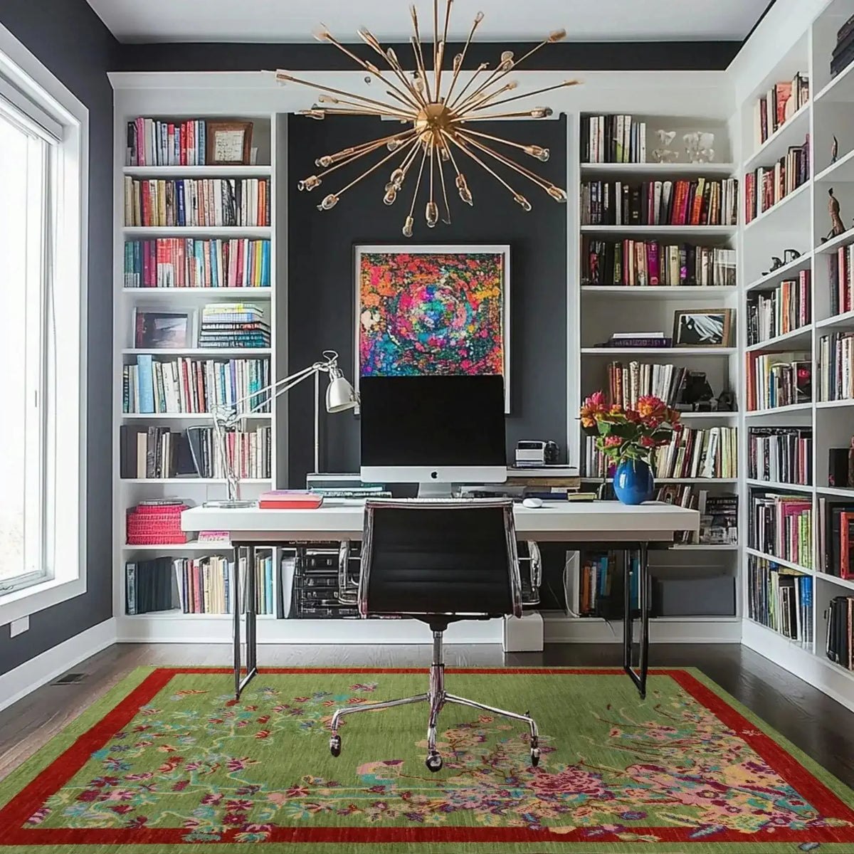 A beautifully styled home office features a hand-knotted area rug with a vibrant red border and intricate spring floral design on a green background. This living room area rug adds a touch of elegance and color to the modern space, blending seamlessly with the bookshelf-lined walls and sleek desk setup.