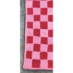 Close-up of a Red Checker Jute Rug measuring 2 x 3 ft, showcasing its vibrant red and pink checkered pattern. This area rug is perfect for adding a pop of color to your office or as a stylish addition to large area rugs for living rooms.