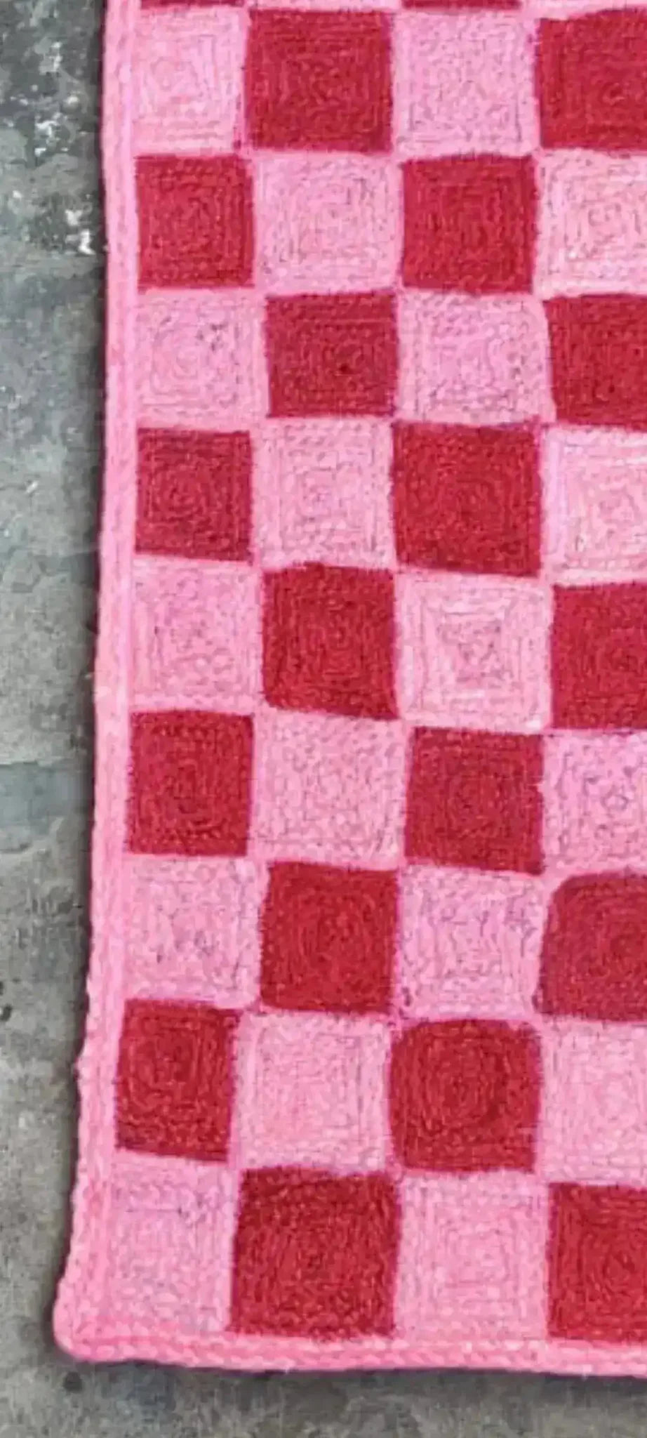 Close-up of a Red Checker Jute Rug measuring 2 x 3 ft, showcasing its vibrant red and pink checkered pattern. This area rug is perfect for adding a pop of color to your office or as a stylish addition to large area rugs for living rooms.