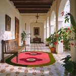 A vibrant red twin flowers hand tufted wool area rug placed in a stylish corridor, surrounded by elegant wooden benches and lush plants. Perfect for large living rooms or dining areas, this contemporary rug brings a pop of color and warmth to any space. Ideal for those seeking living room rugs in 8x10 dimensions.
