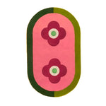 Top view of the Red Twin Flowers Hand Tufted Wool Rug, featuring a contemporary design with two red floral patterns on a pink background, surrounded by a green border. Perfect for large living rooms or dining areas, this 8x10 wool area rug adds a vibrant touch to any space.