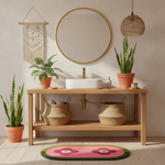 Bathroom interior with wooden vanity, round mirror, plants, floral wool rug, and decorative items.