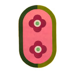 Top view of the Red Twin Flowers Hand Tufted Wool Rug, featuring a contemporary design with two red floral patterns on a pink background, surrounded by a green border. Perfect for large living rooms or dining areas, this 8x10 wool area rug adds a vibrant touch to any space.