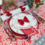 Red & White Delight Placemats in festive table setting — red damask print, scalloped white edge, with bow-folded red napkin