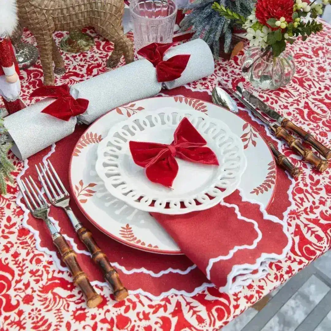 Red & White Delight Placemats in festive table setting — red damask print, scalloped white edge, with bow-folded red napkin