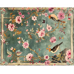 A beautifully crafted area rug featuring a vibrant floral design with birds, perfect for adding elegance to living rooms or offices. This hand-tufted wool rug showcases pink flowers and intricate branches on a rich green background, ideal for those seeking exquisite living room area rugs.