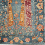 A stunning hand-knotted area rug featuring an intricate vintage design with vibrant floral patterns in shades of blue, orange, and pink. Perfect for enhancing the elegance of any living room area, this rug brings a touch of timeless charm and sophistication.
