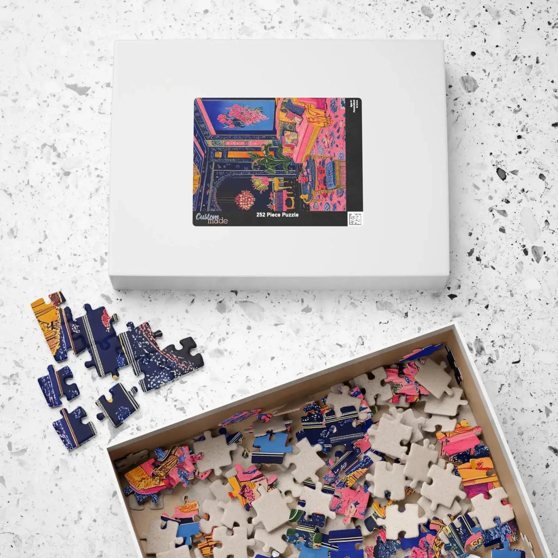 White Regal Eclectic Puzzle box with image label on terrazzo surface beside open box overflowing with loose colorful pieces