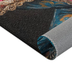 Rolled corner of the Regal Renaissance Chihuahua rug showing dark charcoal surface with blue floral jacket edge and grey non-slip backing with zigzag seam
