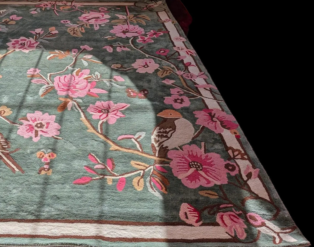 Decorative rug with floral and bird patterns on a wooden floor.