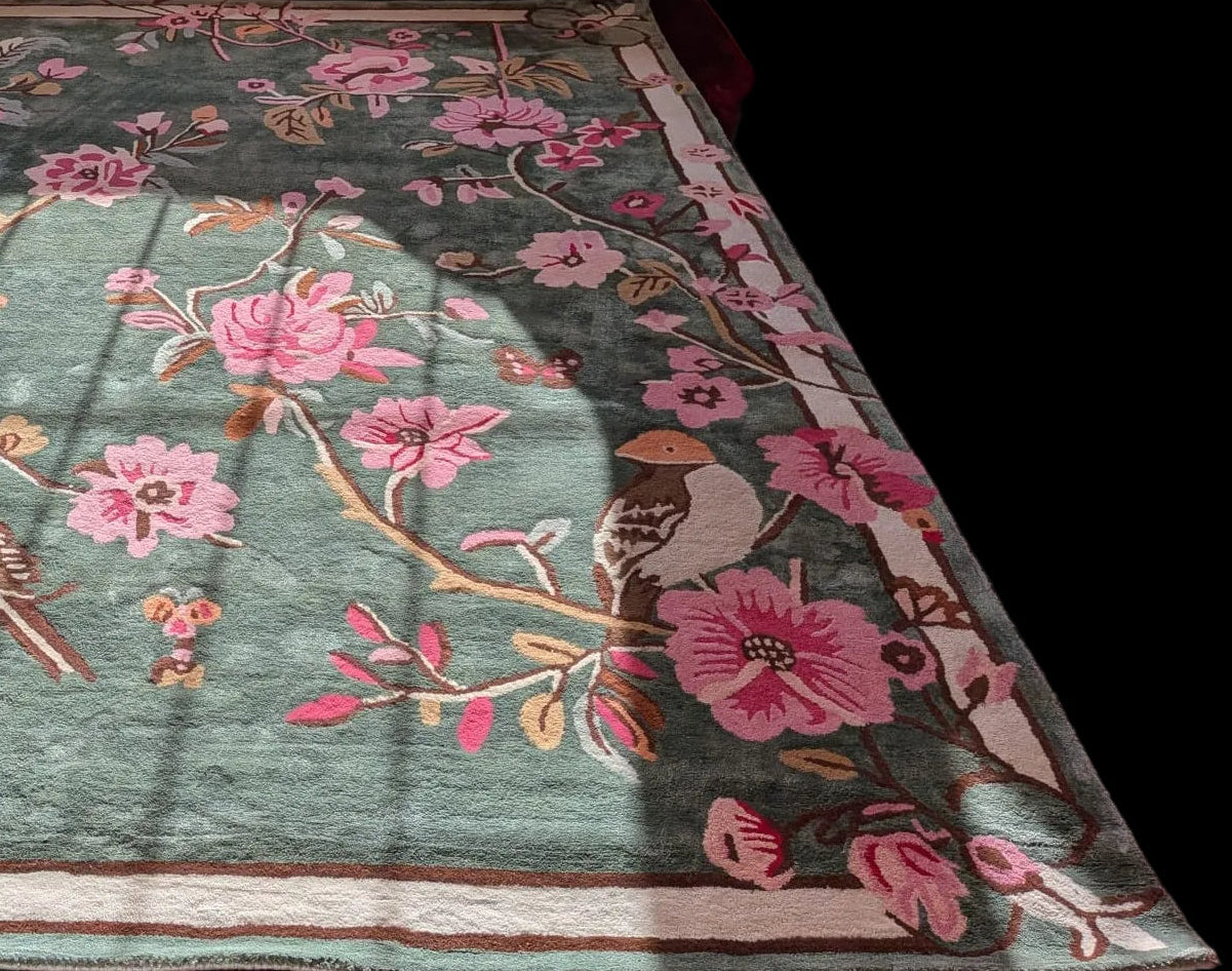 Decorative rug with floral and bird patterns on a wooden floor.
