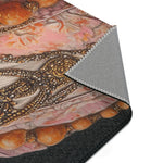 Folded corner of Renaissance Rooster Couture Rug showing dark fabric with embroidered rooster costume bead and floral detail, grey non-slip backing at edge