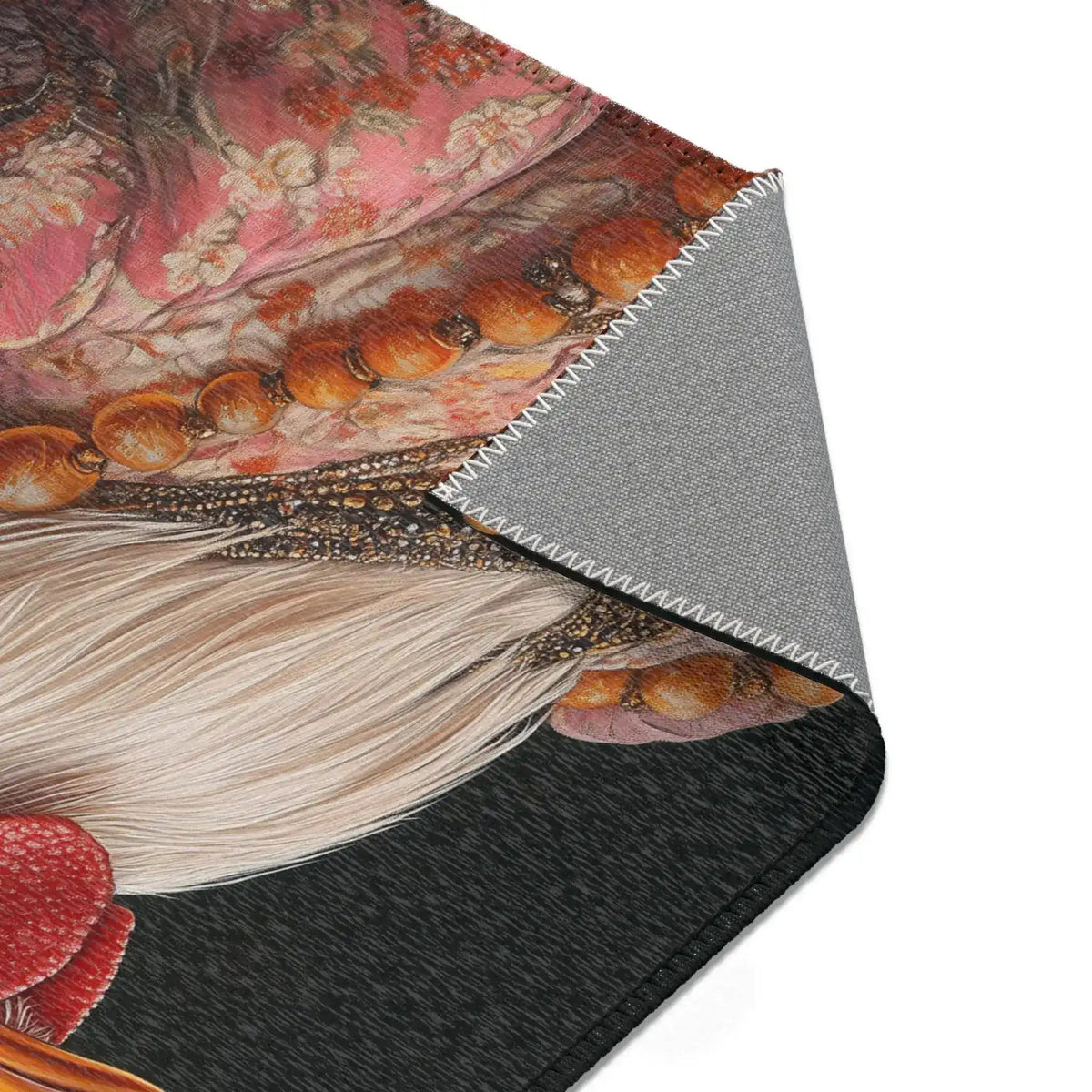 Corner detail of Renaissance Rooster Couture Rug folded, showing pink floral embroidered costume fabric and wooden bead necklace on dark ground, grey backing exposed