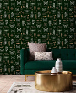 Retro botanical insect lattice wallpaper behind emerald velvet sofa with hammered gold drum table