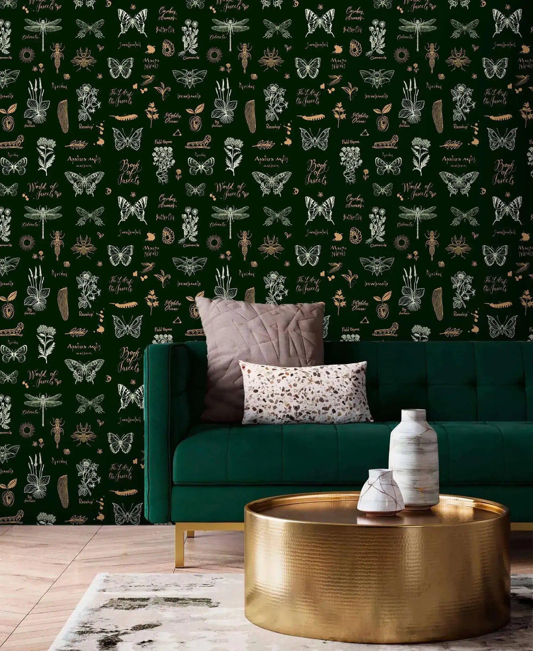 Retro botanical insect lattice wallpaper behind emerald velvet sofa with hammered gold drum table