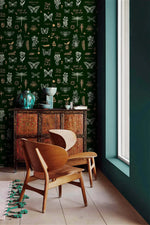 Retro botanical insect wallpaper, dark green with butterflies and dragonflies, by carved cabinet and wood chairs