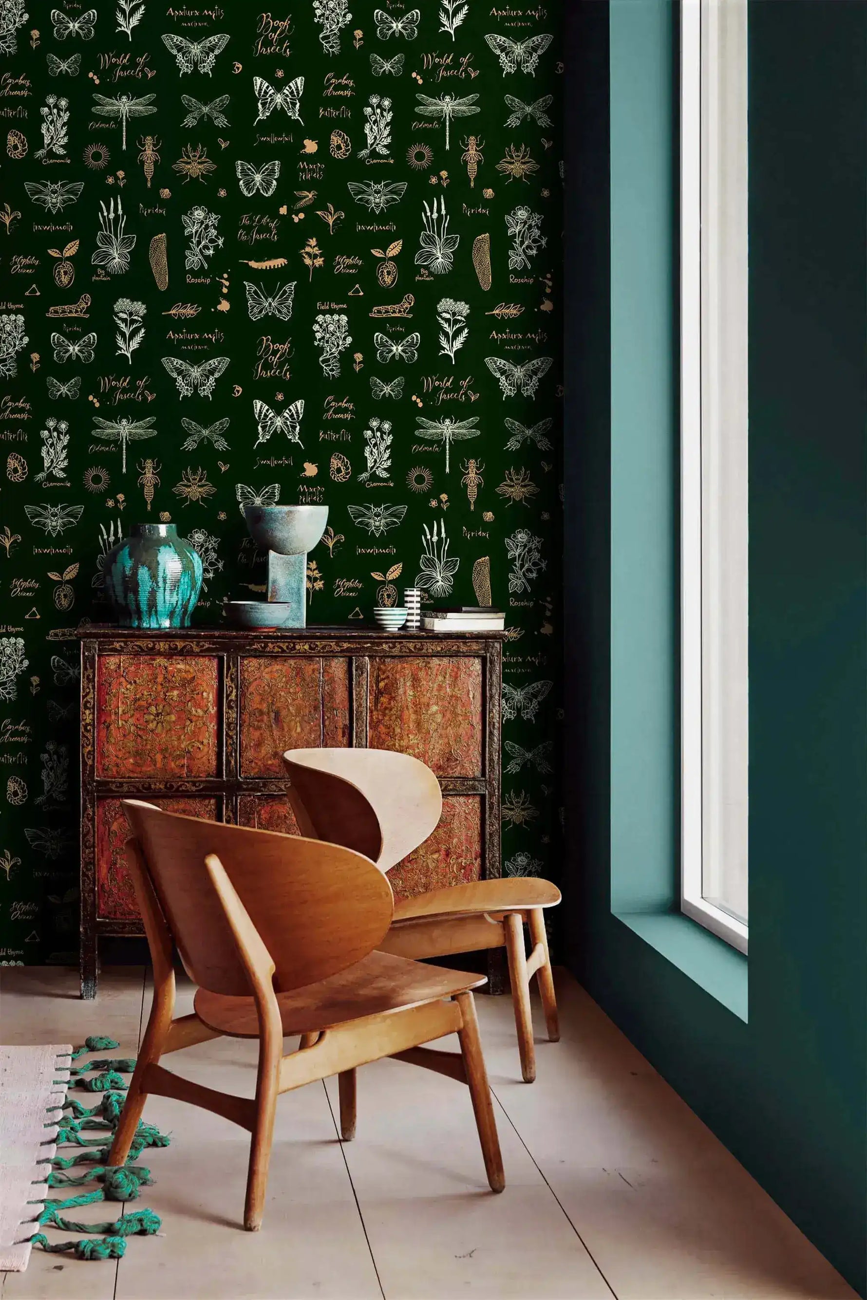 Retro botanical insect wallpaper, dark green with butterflies and dragonflies, by carved cabinet and wood chairs