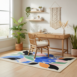 Home office with a wooden desk, chair, and colorful rug on a light wood floor.
