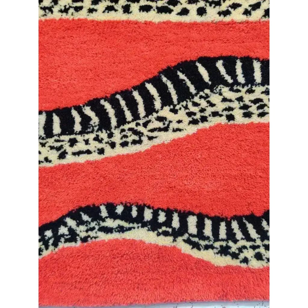 Close-up of the Retro Red Snake Hand Tufted Wool Rug, showcasing its bold red background with striking black and white snake-like patterns. Perfect for adding a vintage touch to a dining room or enhancing large living room spaces with its vibrant design, this wool area rug fits seamlessly into both living room and formal dining room settings.