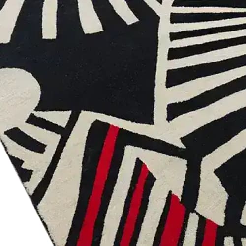Close-up of the Rhythmic Rays Hand Tufted Area Rug featuring a striking abstract design with bold black, white, and red patterns. This wool rug is perfect for enhancing the aesthetic of living room and dining room spaces.