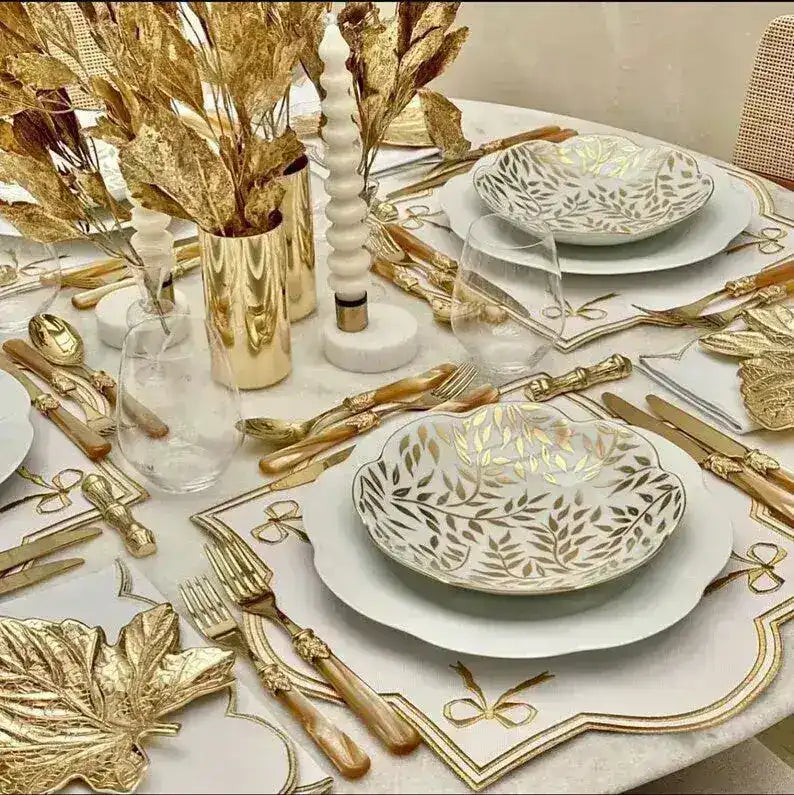 ribboned radiance placemat white gold ribbon bow embroidery gold leaf bowl white plates ornate gold cutlery crystal stemware
