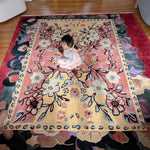 Child playing on a large floral rug in a room with wooden flooring.