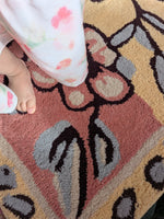 Close-up of a child's feet on a patterned rug with floral designs.