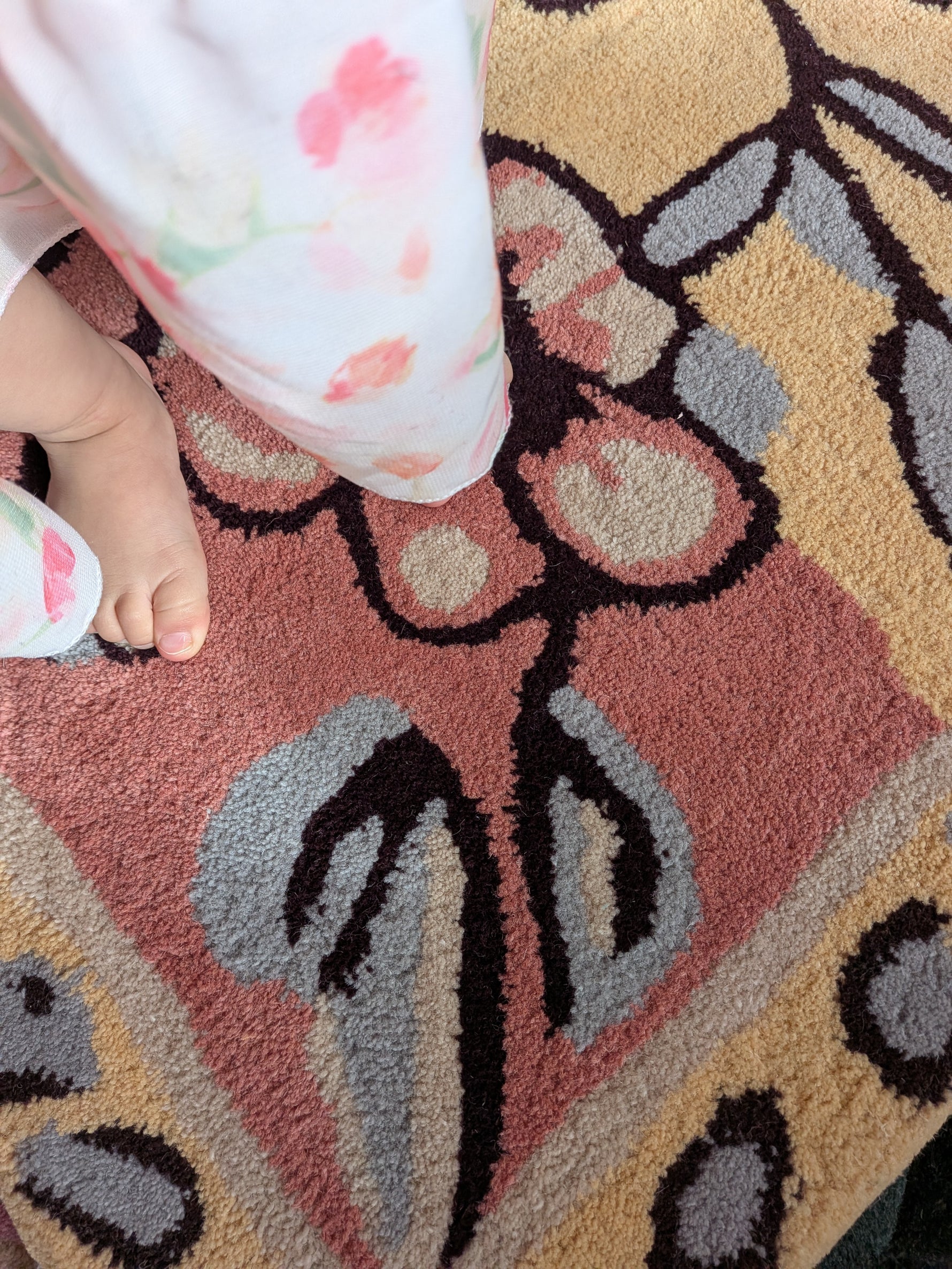 Close-up of a child's feet on a patterned rug with floral designs.