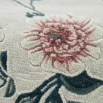 Close-up of a floral patterned rug with pink flowers and green leaves.