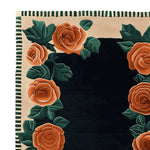 Close-up of the Rosewood Garden Bloom Hand Tufted Area Rug, showcasing its intricate floral design with vibrant orange roses and lush green leaves against a deep black background. Perfect for adding a touch of elegance to living room area rugs. This 8x10 wool rug highlights exquisite craftsmanship, making it an ideal choice for those seeking a stunning floral rug for their home.