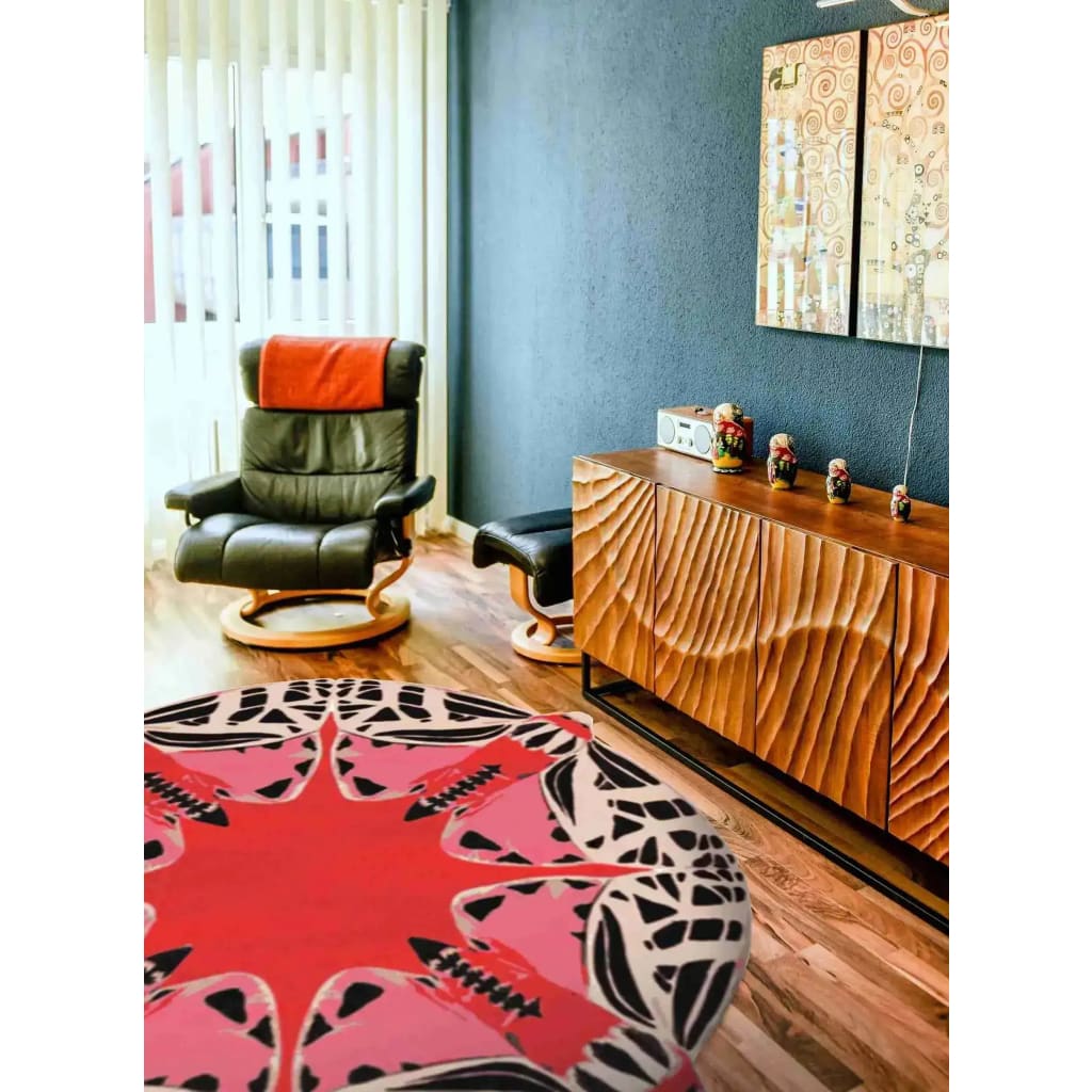 A stylish living room featuring a Round Abstract Butterfly Hand Tufted Rug in vibrant red tones. This area rug serves as a striking centerpiece, complementing the modern decor and wooden flooring. Ideal for dining rooms, this wool rug adds a splash of color and warmth, perfect for enhancing living room aesthetics.