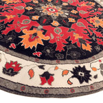 Vibrant round area rug featuring an intricate medallion design with red, orange, and black hues, perfect for enhancing bedroom decor. This wool rug, reminiscent of Persian rugs, adds a touch of elegance and warmth to any bedroom space.