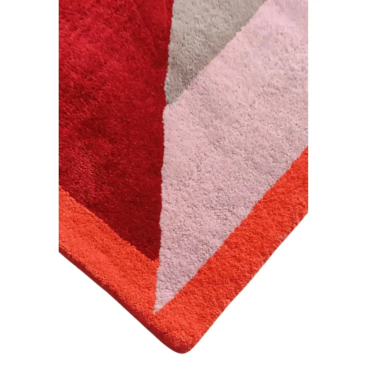 Rounded corner detail of the retro rug where red, blush and coral blocks meet in soft pile