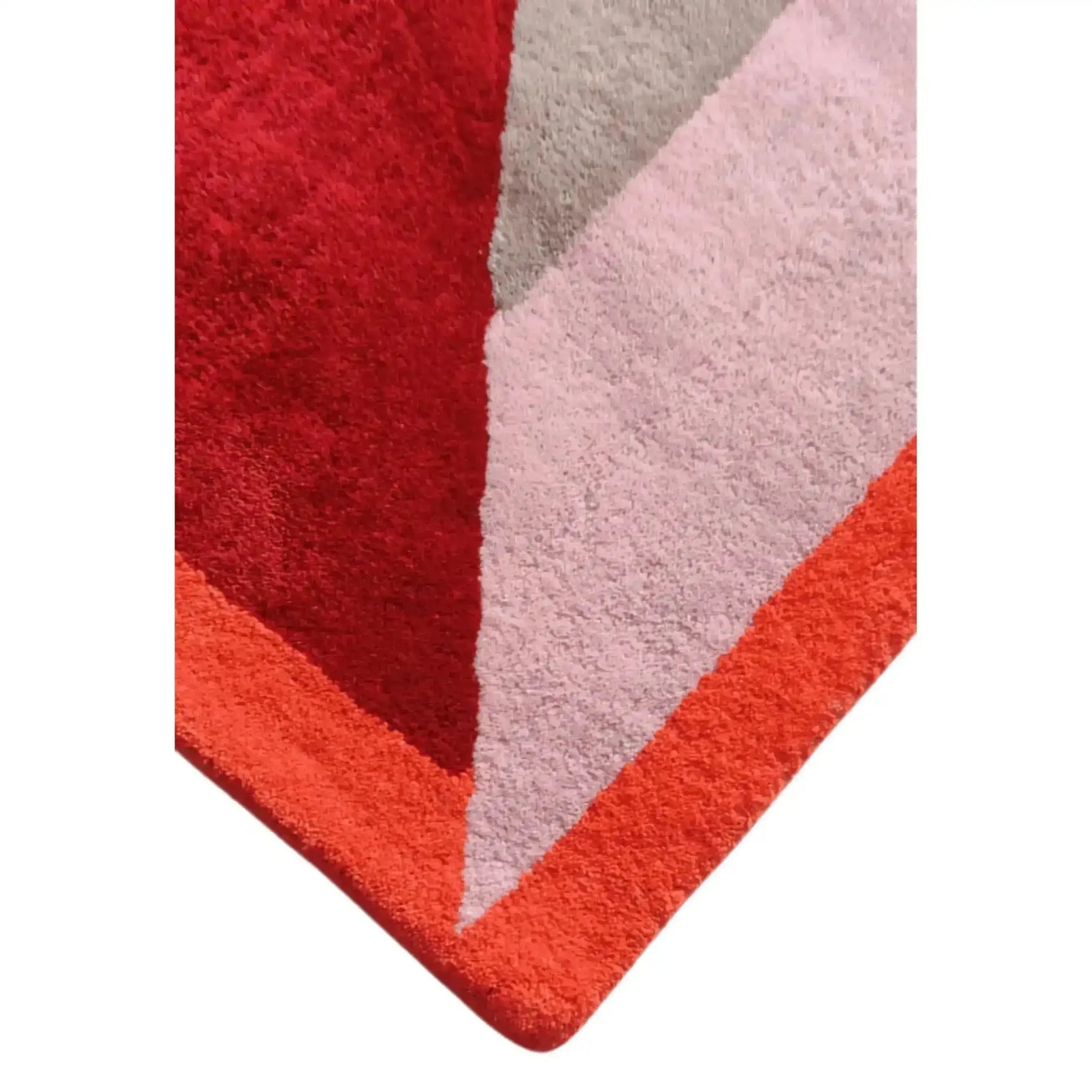 Rounded corner detail of the retro rug where red, blush and coral blocks meet in soft pile