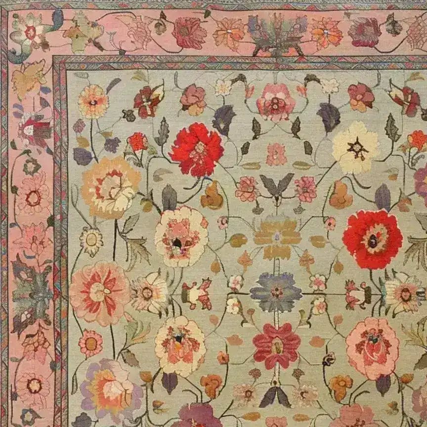 A beautifully detailed Royal Elegance Hand Knotted Area Rug showcasing an intricate floral design. This square area rug, perfect for large living room spaces or bedrooms, features a vintage Persian style with vibrant red, pink, and cream flowers on a soft background. Made from high-quality wool, this rug adds a touch of timeless elegance to living room or bedroom decor.