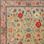 A beautifully detailed Royal Elegance Hand Knotted Area Rug showcasing an intricate floral design. This square area rug, perfect for large living room spaces or bedrooms, features a vintage Persian style with vibrant red, pink, and cream flowers on a soft background. Made from high-quality wool, this rug adds a touch of timeless elegance to living room or bedroom decor.