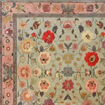 A beautifully detailed Royal Elegance Hand Knotted Area Rug showcasing an intricate floral design. This square area rug, perfect for large living room spaces or bedrooms, features a vintage Persian style with vibrant red, pink, and cream flowers on a soft background. Made from high-quality wool, this rug adds a touch of timeless elegance to living room or bedroom decor.