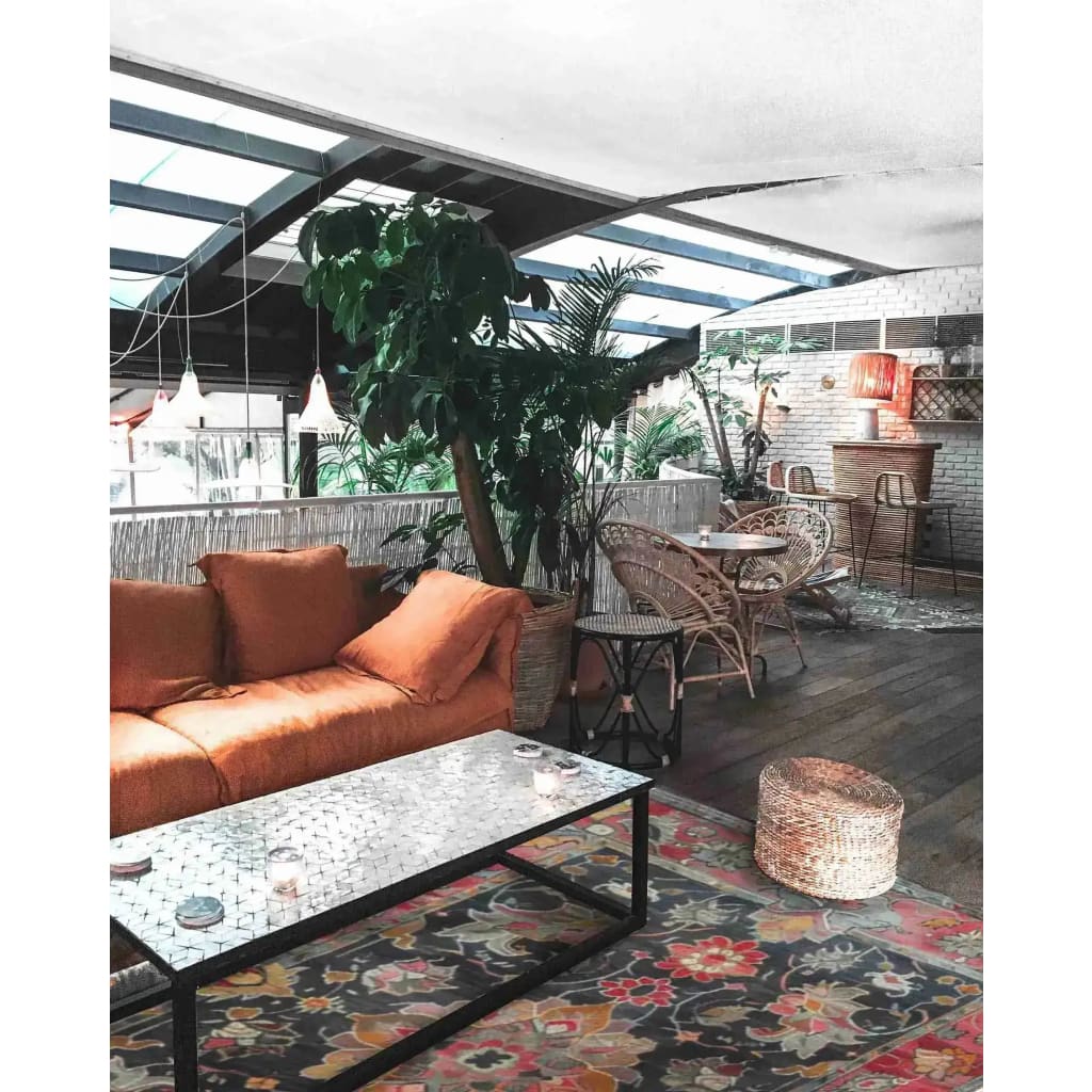 A cozy living room featuring a Royal Majesty Hand Tufted Area Rug with a vibrant floral design, perfect for large living rooms or formal dining rooms. The wool rug adds a touch of elegance to the space, complemented by a comfortable orange sofa and wicker furniture.