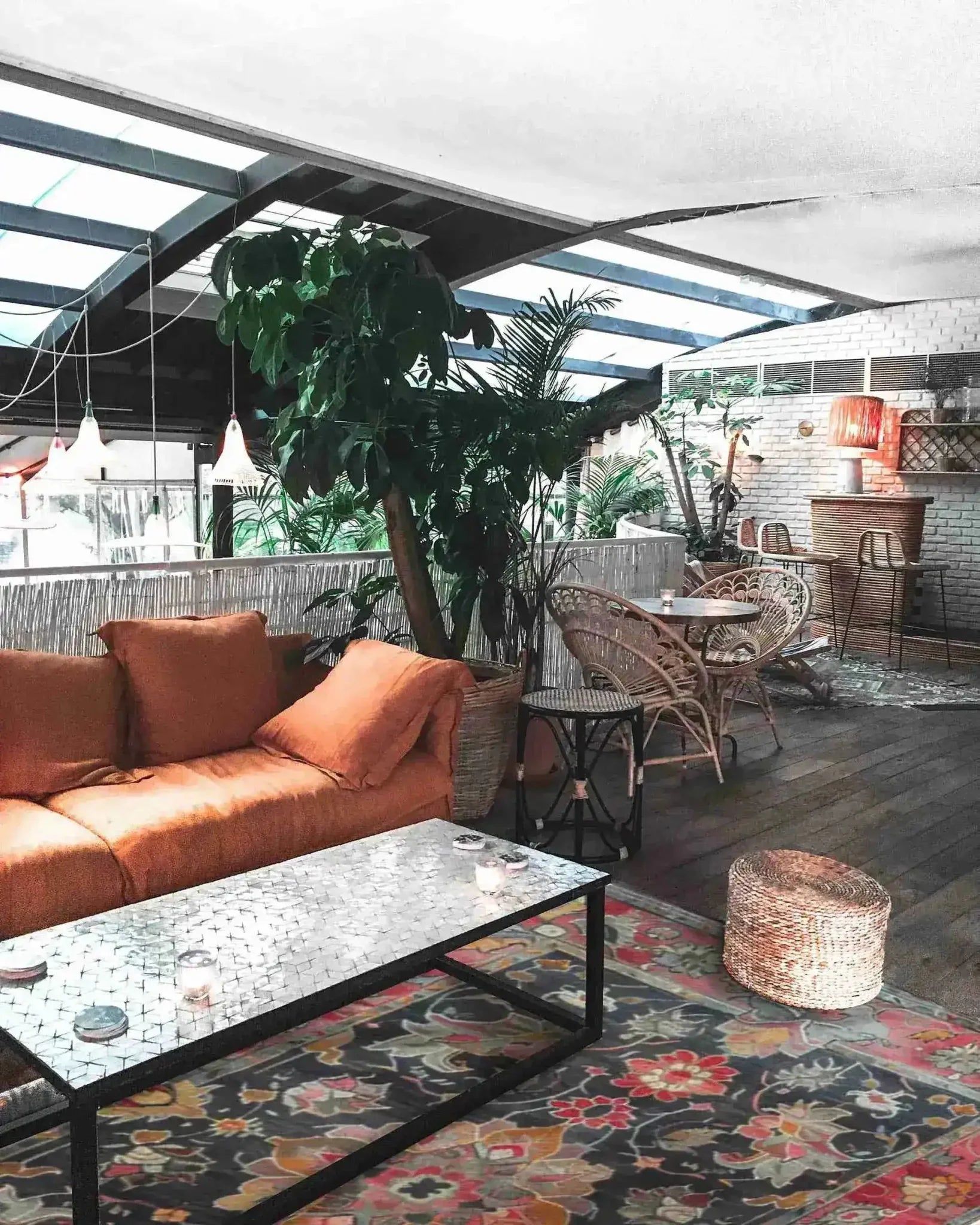 A cozy living room featuring a Royal Majesty Hand Tufted Area Rug with a vibrant floral design, perfect for large living rooms or formal dining rooms. The wool rug adds a touch of elegance to the space, complemented by a comfortable orange sofa and wicker furniture.