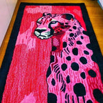 A vibrant, hand-tufted wool area rug featuring an abstract design of a pink and black spotted cheetah. This contemporary rug, perfect for a hallway runner or a bold addition to a living room, showcases intricate details and a modern aesthetic suitable for various spaces, including kitchens and bathrooms.