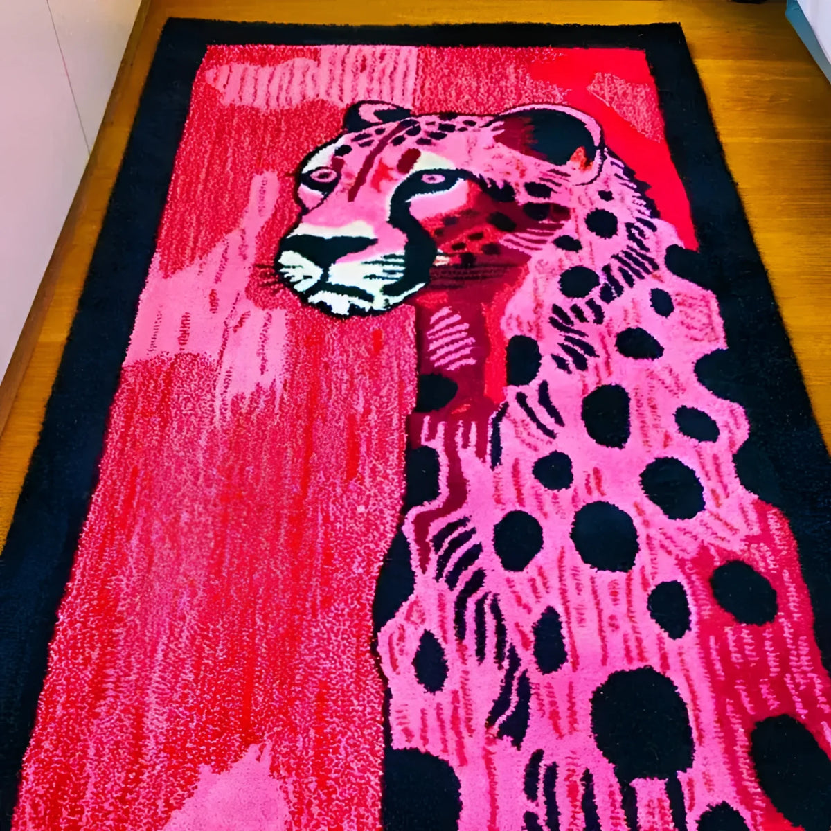 A vibrant, hand-tufted wool area rug featuring an abstract design of a pink and black spotted cheetah. This contemporary rug, perfect for a hallway runner or a bold addition to a living room, showcases intricate details and a modern aesthetic suitable for various spaces, including kitchens and bathrooms.