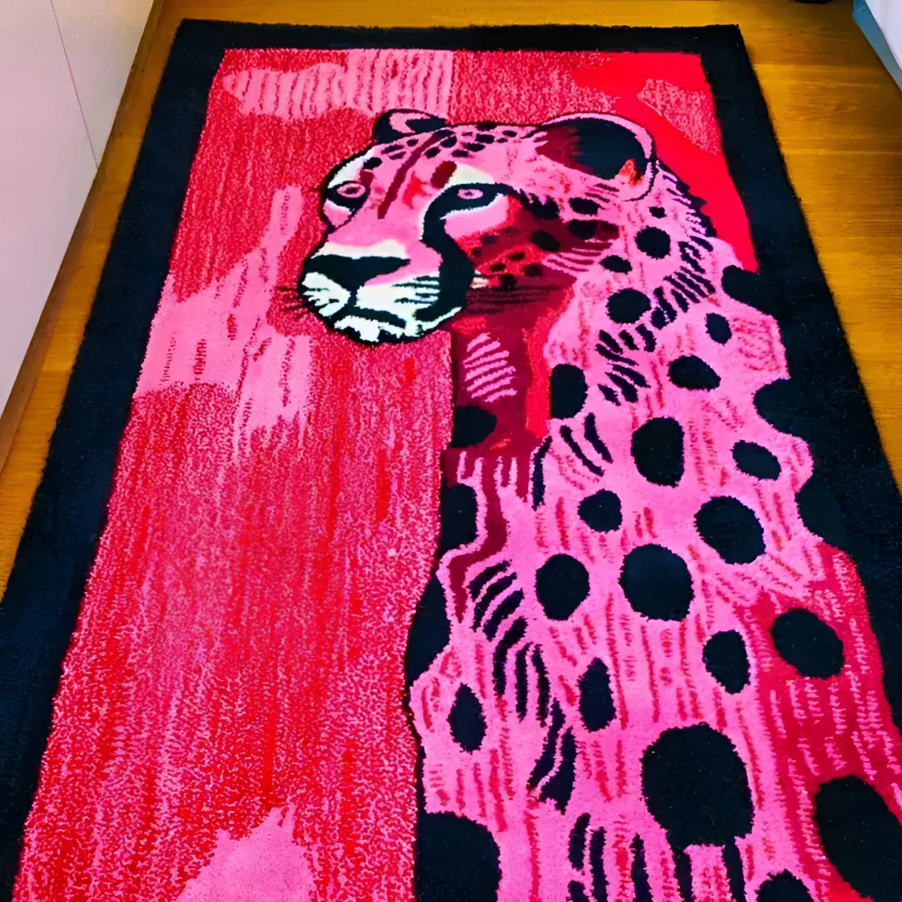 A vibrant, hand-tufted wool area rug featuring an abstract design of a pink and black spotted cheetah. This contemporary rug, perfect for a hallway runner or a bold addition to a living room, showcases intricate details and a modern aesthetic suitable for various spaces, including kitchens and bathrooms.