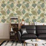 Sage and beige ginkgo leaf wallpaper above white panelling with black leather sofa and shelf