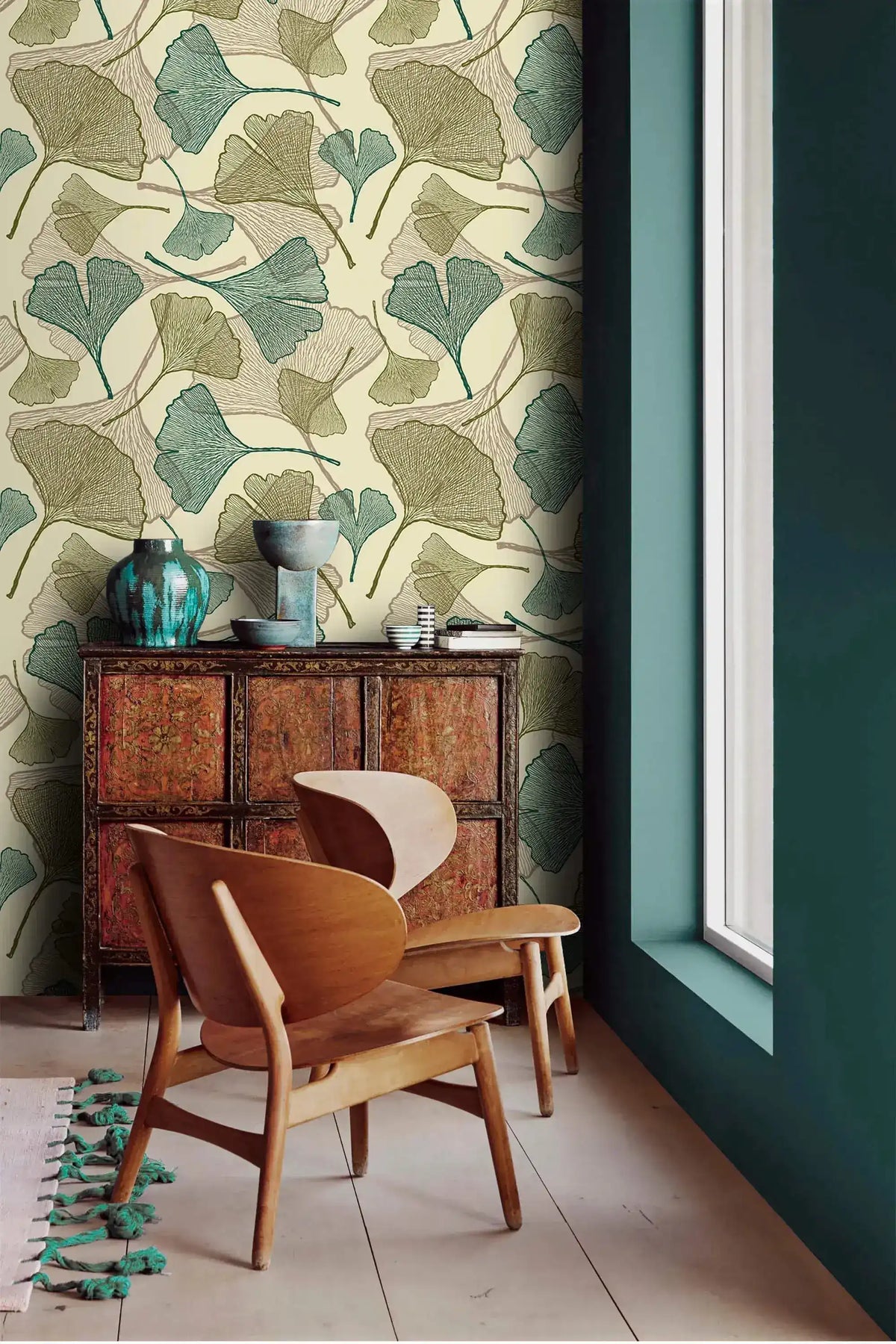 Sage ginkgo leaf wallpaper in corner with carved wood cabinet, teal vases and curved wood chair