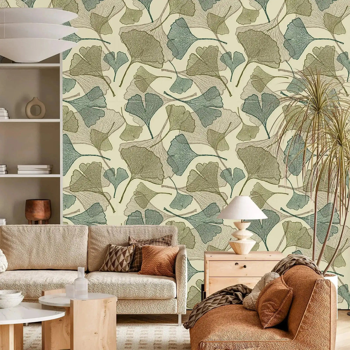 Sage green and beige ginkgo leaf wallpaper in living room with cream sofa and rust armchair