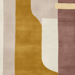 A contemporary area rug with an abstract geometric design featuring warm tones of mustard, cream, and mauve. This wool rug is perfect for large living rooms, adding a modern touch with its unique pattern and soft texture.