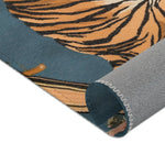 Rolled corner of the Savage Symphony Vintage Tapestry showing amber black tiger striped body on dusty blue with grey non-slip backing and zigzag seam