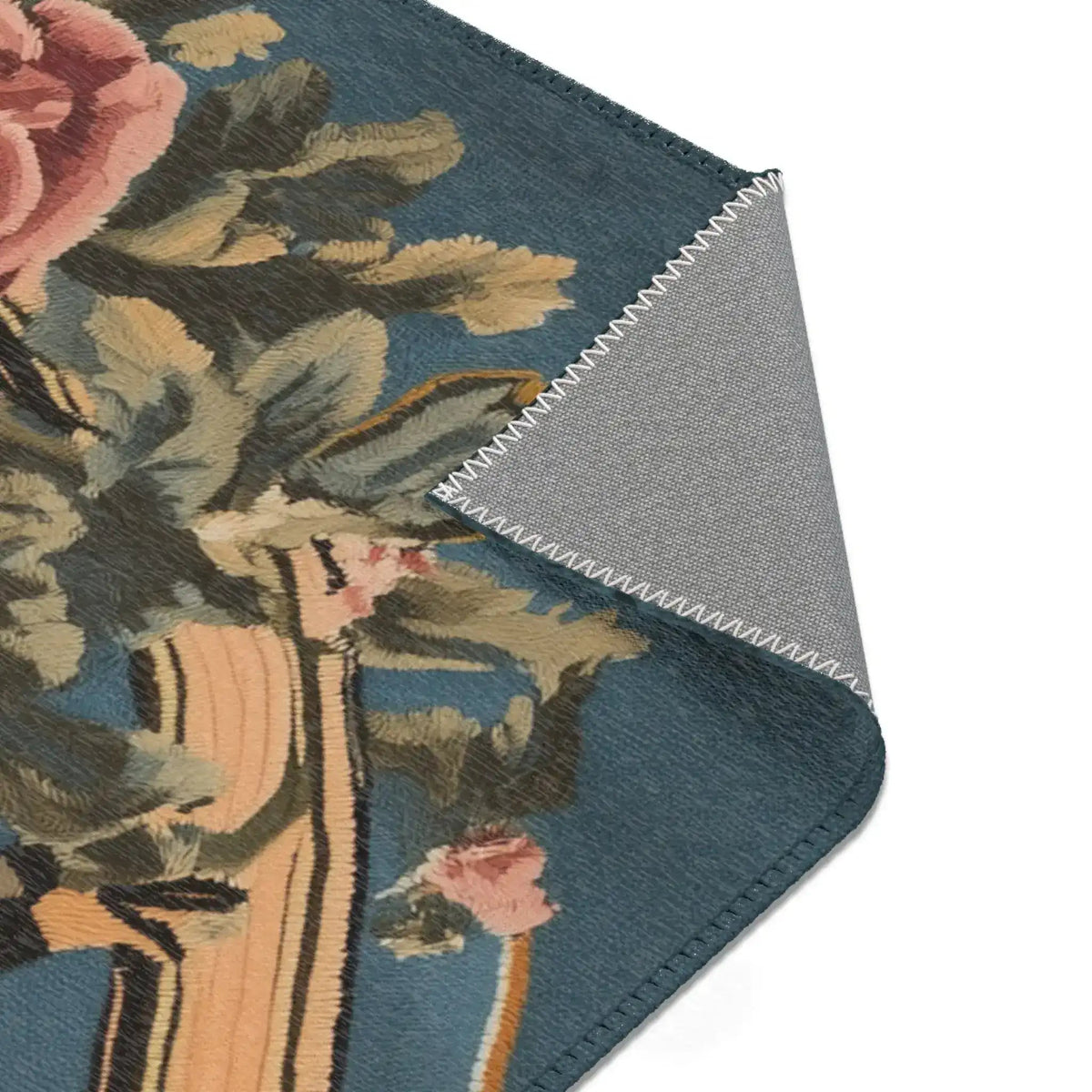Folded corner showing layered pink rose and dense green leaves from the floral wreath on blue-grey on the Savage Symphony Vintage Tapestry of Fierce Elegance