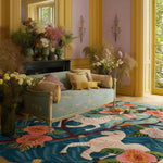 A vibrant living room featuring the Savanna Blossom Hand Tufted Area Rug in an 8x10 size. This floral wool rug showcases a lively design with bold pink flowers and intricate patterns, adding a touch of elegance to the space. Set in a cozy living room with pastel walls and a classic sofa, this rug enhances the room's aesthetic with its rich colors and soft texture.